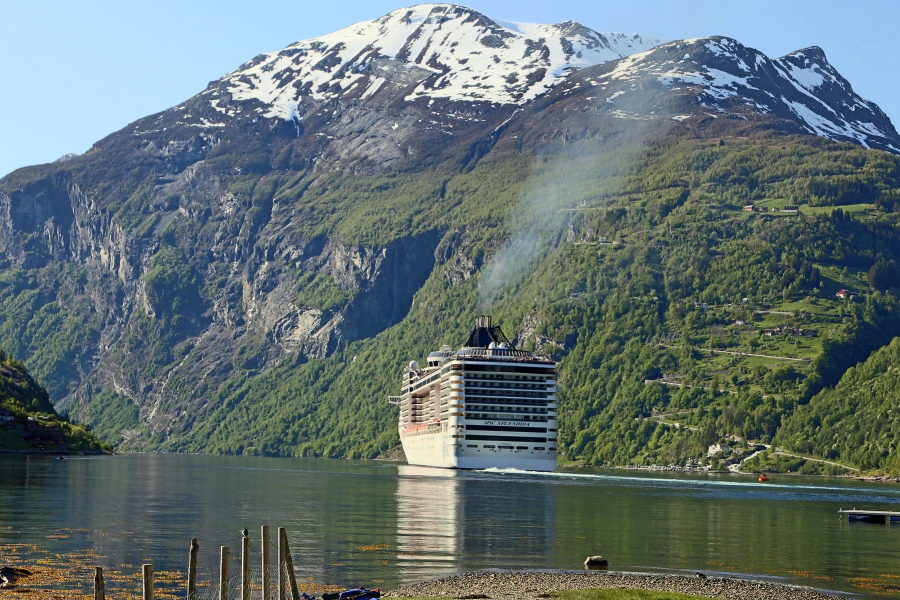 A cruise ship dwarfed by the steep green walls of Geirangerfjord, Norway