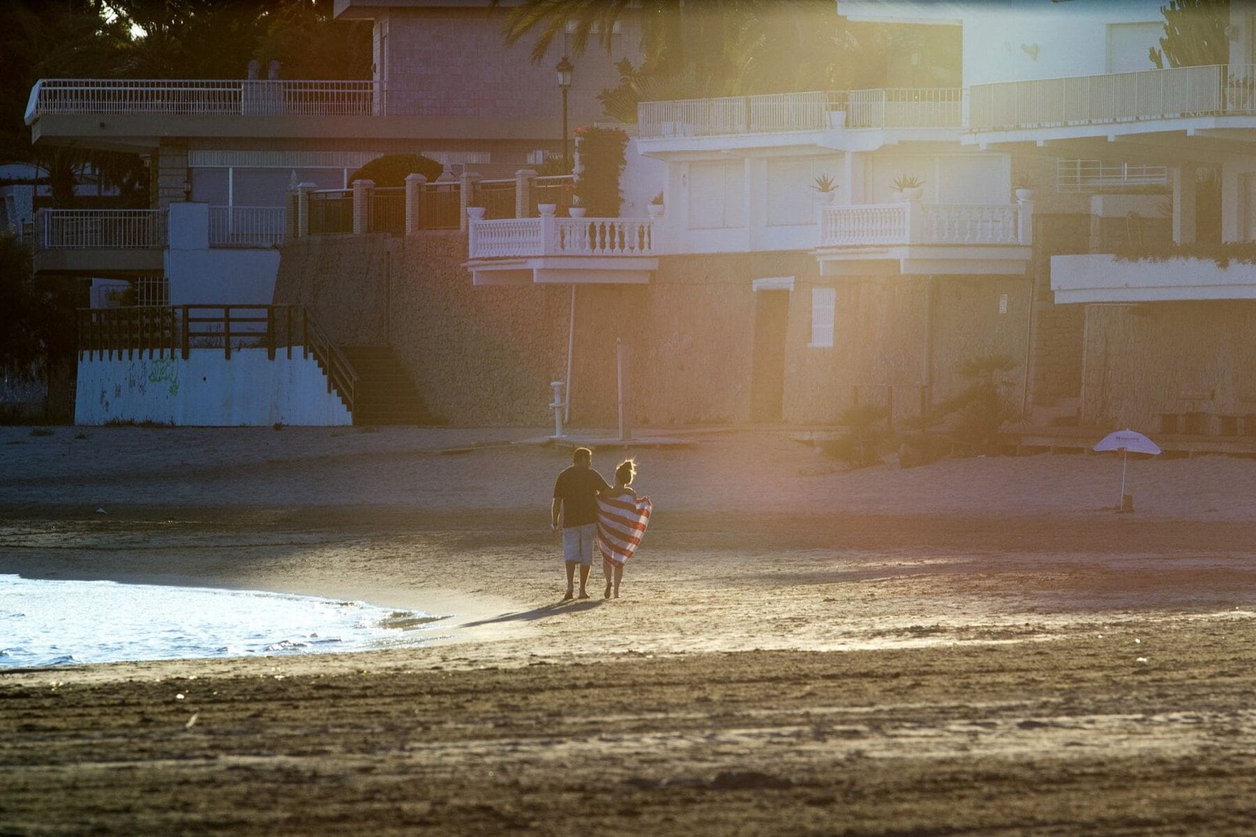 Two people walking along a beach at dusk