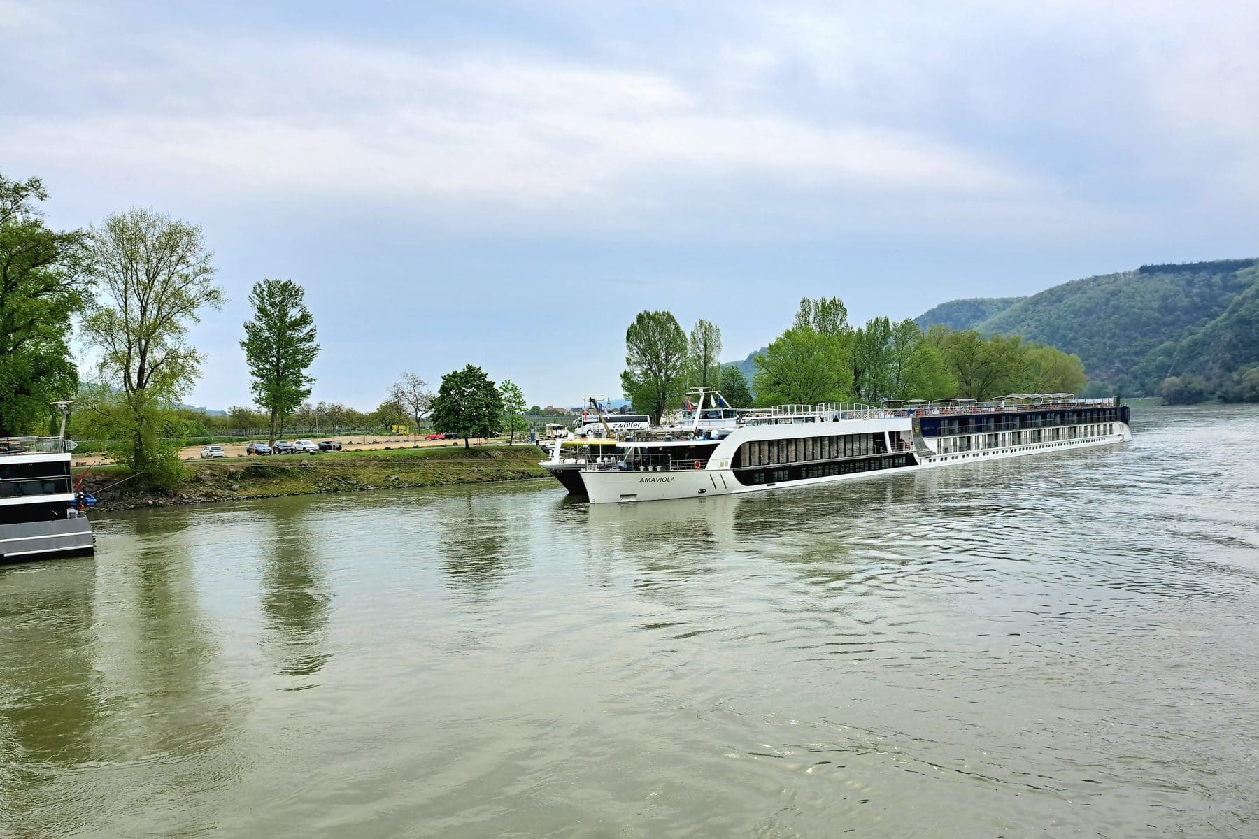 River ships passing the wooded banks of the Danube at Dürnstein in the Wachau valley, Austria
