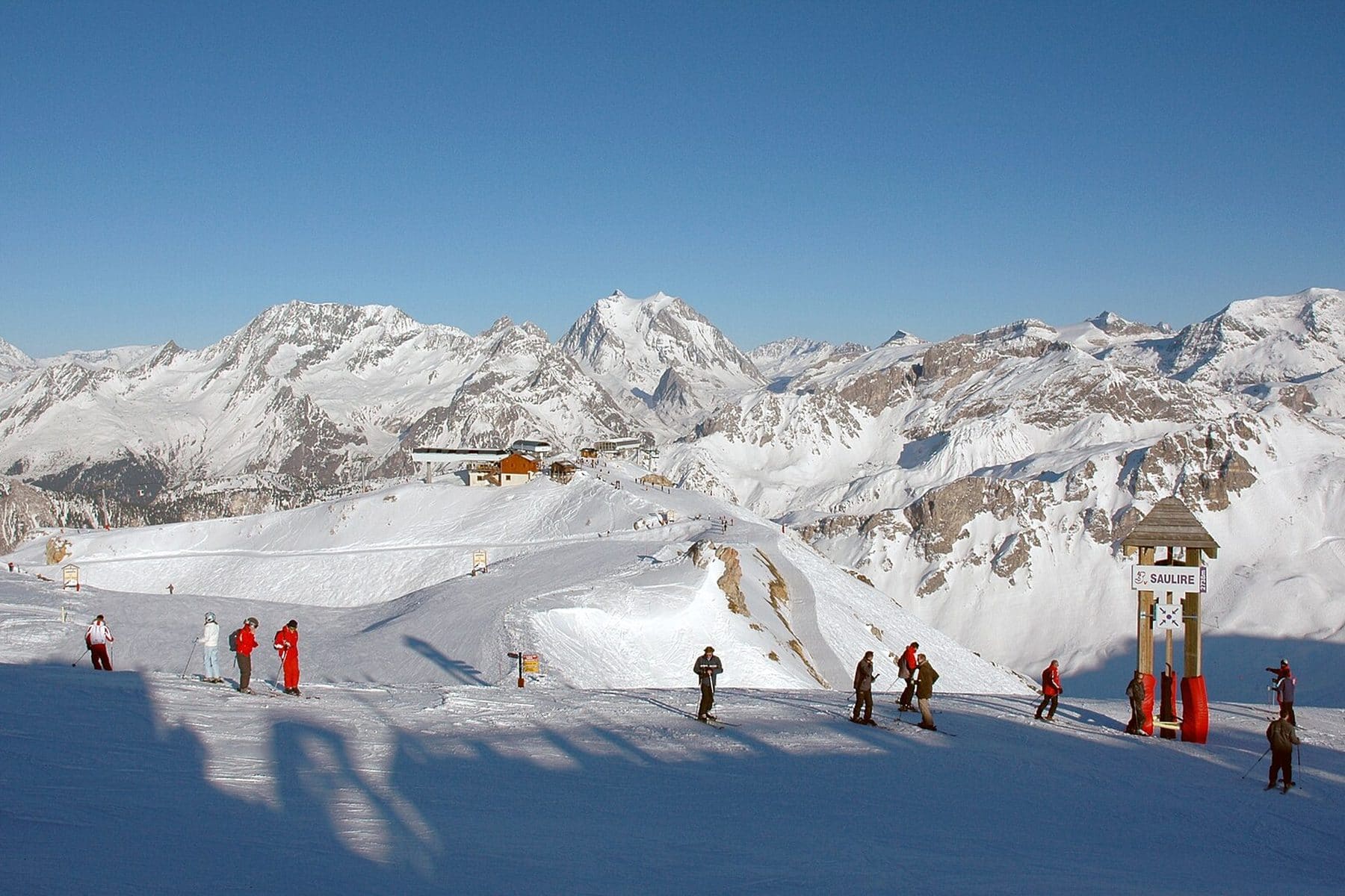 Skiers on a sunny piste above Courchevel, looking east from Saulire