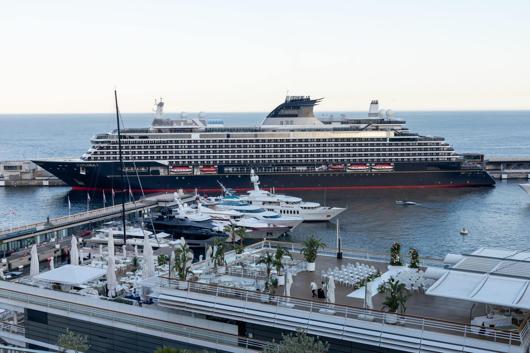 Explora I alongside in Monaco at dusk, with a terrace set for an evening reception in the foreground