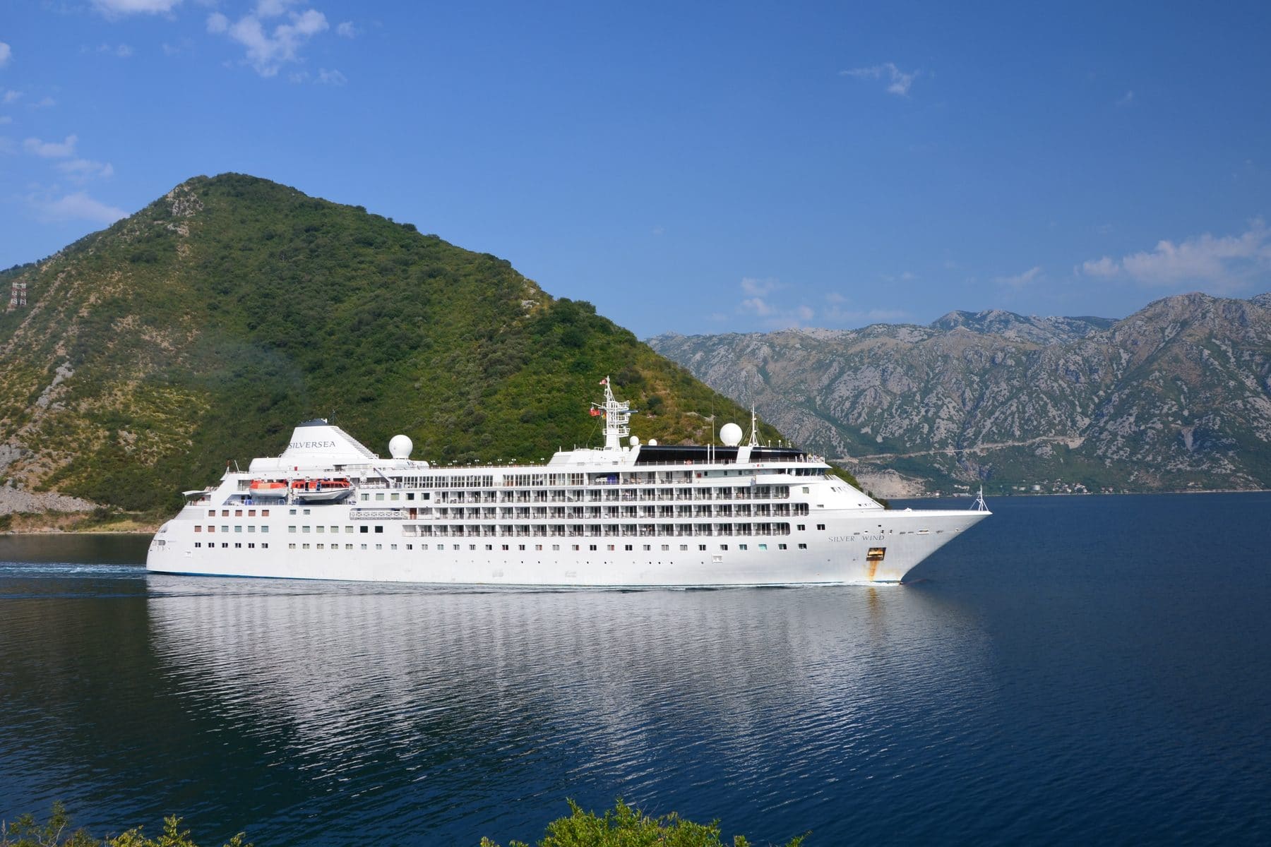 Silversea's Silver Wind sailing the Bay of Kotor, Montenegro, with mountains rising behind the town